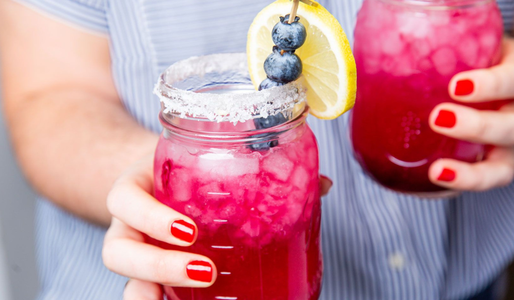 Blueberry Lemonade Margaritas Delish Header - Woman Holding it with red nails